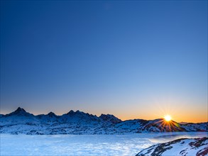 Sunrise over snowy mountains above the frozen Kong Oscar Fjord