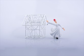 Sufi dervish and a little metal house on a white background