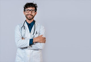 Portrait of young doctor with arms crossed. Smiling doctor with crossed arms on isolated background. Latin doctor with crossed arms on isolated background