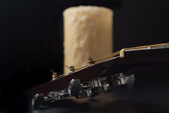 Spanish guitar neck with a candle in the background on a black background