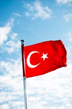 Red Turkish flag on pole on a cloudy sky