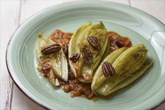 Steamed chicory with pecan nuts served on a plate