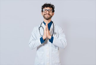 Smiling doctor putting palms together on isolated background. Handsome doctor with hands together isolated. Young doctor with palms together
