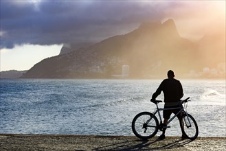 Cyclist in front of the sea during late afternoon at Arpoador beach in Ipanema