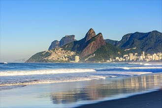 Dawn in the city of Rio de Janeiro with the empty Ipanema beach with the reflection of the buildings in the wet sand