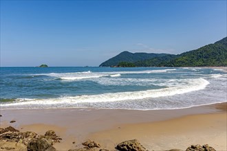 Panoramic image of paradisiacal beach with the meeting of the mountains and rainforest with the sea in Bertioga in the state of Sao Paulo