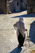 Old lady wearing the clothes and Islam veil walking the streets of Goreme in Cappadocia