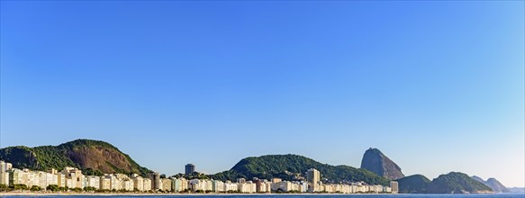 Panoramic image of Copacabana Beach and Sugar Loaf Mountain with its buildings and hills seen with the sea
