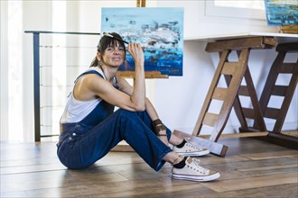 Portrait of a woman artist siting on the floor while looking at camera