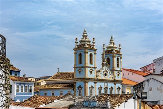 Tower and facade of a historic baroque church emerging from among the houses and roofs of the Pelourinho district