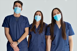 Young doctors dentists with masks in dark blue uniform standing in hallway