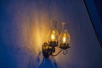 Old lamp adapted for electric light on a rustic and wrinkled wall