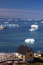 Simple house in front of a bay covered with icebergs