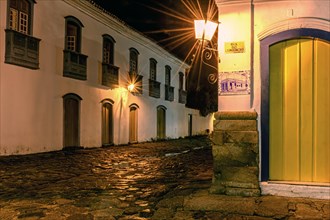 Cobblestone street and reflections in puddles in the historic city of Paraty during a rainy summer night