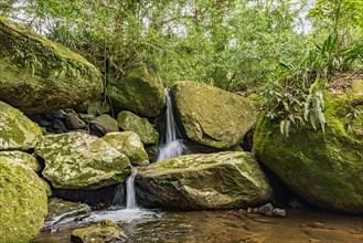 Small waterfall among the rainforest vegetation of Ilhabela island with mossy stones on the north coast of Sao Paulo state