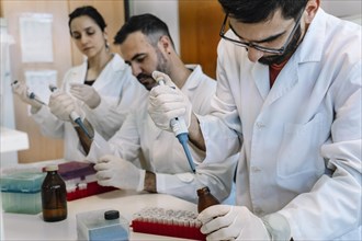 Research laboratory: Team of scientists working with pipette. Microbiology development