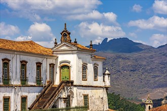 Ancient baroque church in the city of Ouro Preto with the hills and the peak of Itacolomi in the background on a sunny afternoon