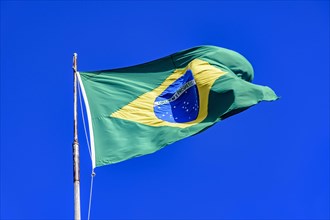 Brazilian flag fluttering in the wind and the blue sky in the background