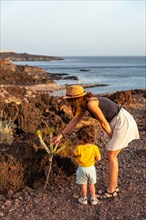 Mother and son on a path looking at a cactus at sunset on the beach of Tacoron on El Hierro