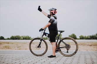 Cyclist taking a selfie on his bike. Chubby cyclist in a sports suit taking a selfie on the road