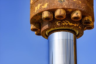 Detail of hydraulic gear with rust on a tractor with blue sky at background