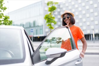Posing with style: black woman wearing orange shirt and sunglasses opening car door