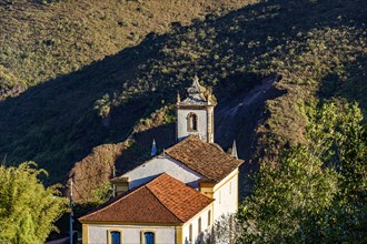 Historic baroque church in Ouro Preto city with hill in the background during the late afternoon