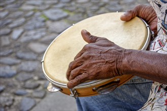 Hands and instrument of percussionist playing tambourine in the streets of the famous Pelourinho neighborhood in the city of Salvador in Bahia