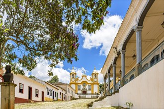 A quiet historic cobblestone street in the city of Tiradentes in Minas Gerais with colonial houses and a baroque church in the background