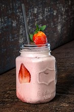 Strawberry Shake in Glass with Straw on Brown Background