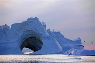 Kayaker in front of huge iceberg