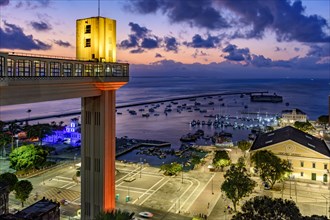 Lacerda elevator illuminated at dusk and with the sea and boats in the background in the city of Salvador