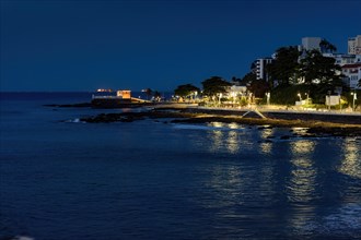Night at Barra beach in Salvador in Bahia illuminated by city lights with reflections on the water