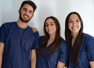 Young smiling doctors dentists in dark blue uniform standing in hallway