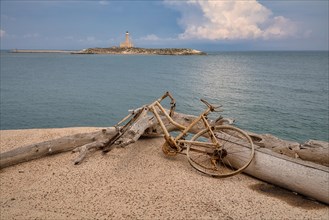 Old bicycle in front of the lighthouse in the port of Vieste
