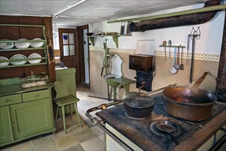 Kitchen with old wood or coal cooker and hand-operated swing pump
