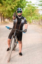 Cyclist giving thumbs up on a road. Professional cyclist doing ok gesture on his bike