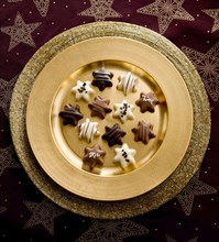 Chocolates as Christmas stars on a golden plate