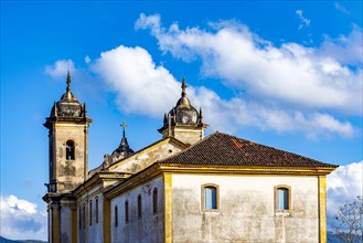 Towers of an old historic baroque church seen from behind in the city of Ouro Preto during dusk with the mountains in the background