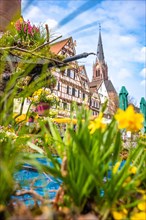 Colourful Easter fountain in front of half-timbered house and church tower in spring
