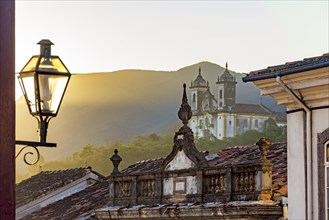 Facade of historic colonial style houses with their lanterns and church in the background in the city of Ouro Preto state of Minas Gerais