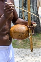 Musician playing a traditional Brazilian percussion instrument called berimbau during a capoeira performance on the streets of Pelourinho in Salvador