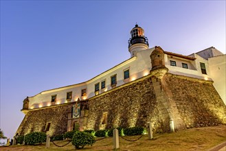 Facade and stone wall of the old and historic fort and lighthouse Barra during sunset in the city of Salvador