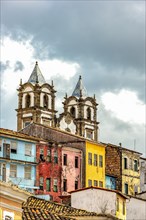 Historic baroque church tower behind the facades of old colonial style houses in Pelourinho in the city of Salvador