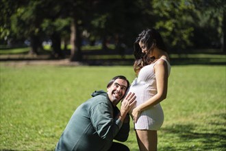 Man listening to his pregnant wife's tummy and smiling
