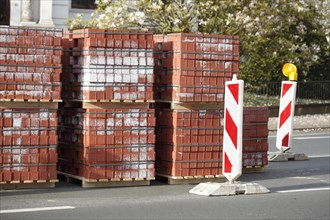 Stacked red building blocks with barrier beacons on a construction site for a cycle path