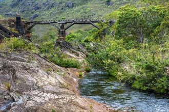 Stream through the vegetation of the Biribiri reserve in Diamantina with an old wooden bridge built by slaves to drain the production of diamonds and destroyed by time