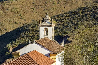 Church and its bell tower seen from behind with the hill and its vegetation in the background in the city of Ouro Preto