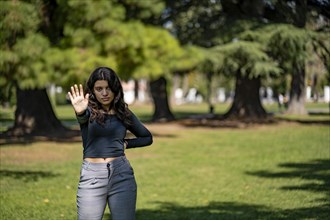 Latin teenager in a park saying no with her hand. Stop concept. Rejection concept. Non-approval concept