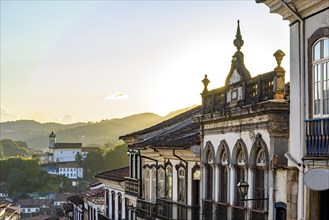 View of colonial style houses facade and historic baroque church in the background on the hills of Ouro Preto city